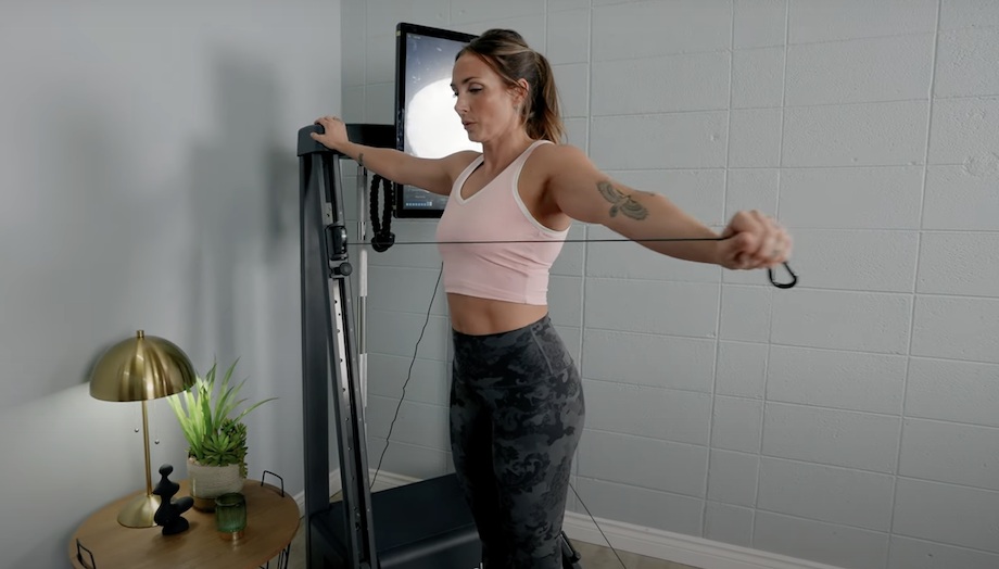 Lindsay Scheele, CPT extends an arm while doing a workout with the Echelon Strength Home.