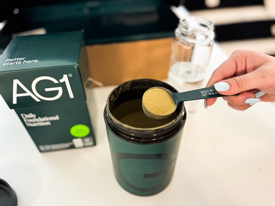 Woman scooping a serving of AG1 supplement