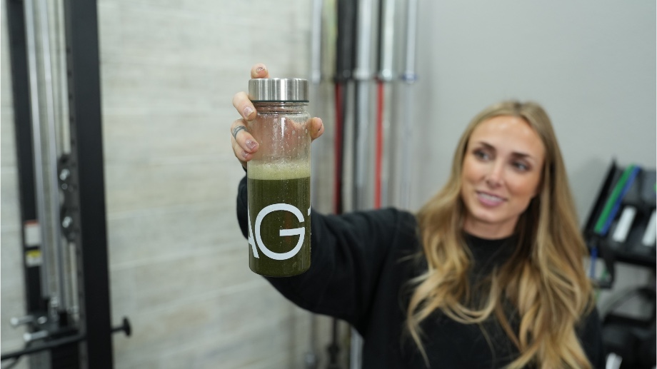 woman holding a mixed bottle of Athletic Greens AG1 greens powder