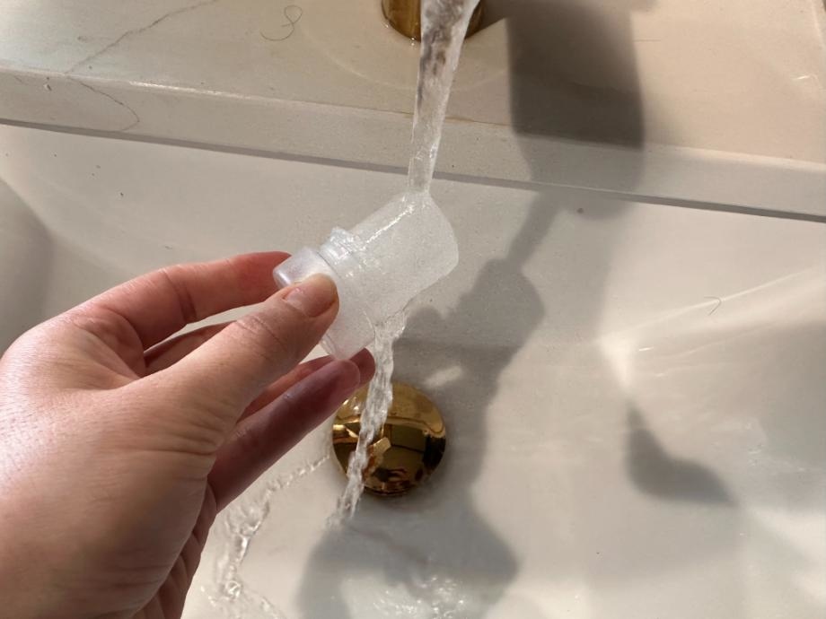 A Crystal Deodorant is held under running water to activate it.