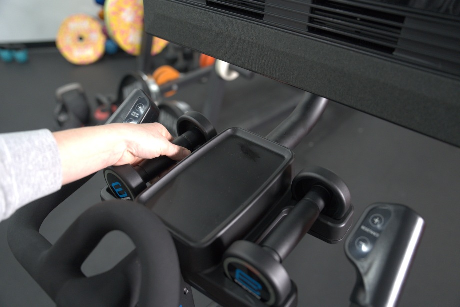 A person lifts a dumbbell from the cradle on a NordicTrack X24 Bike.