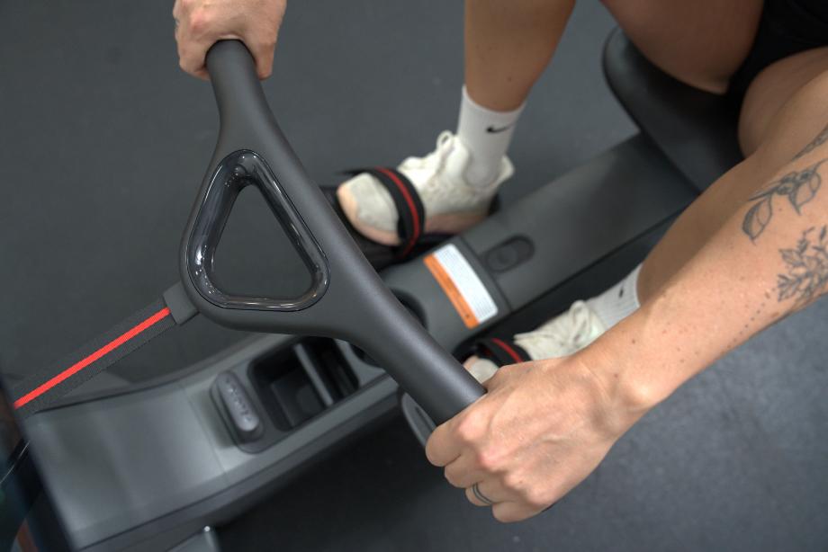 A closeup of a woman grabbing onto the handles of the Peloton Row
