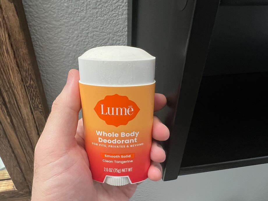 A hand holding a stick of Lume deodorant.