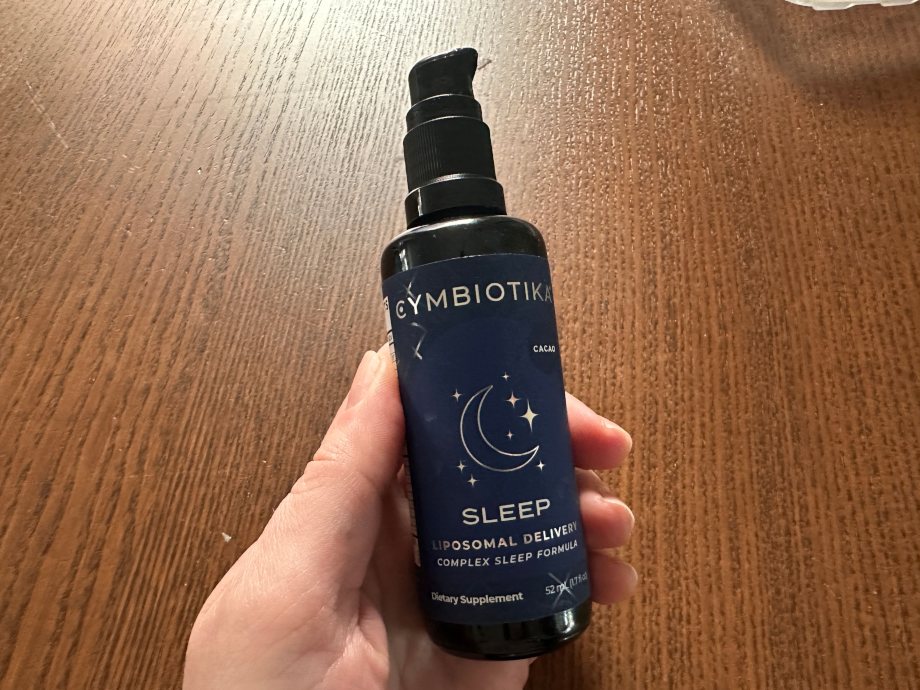 A person holds up a bottle of Cymbiotika Sleep.