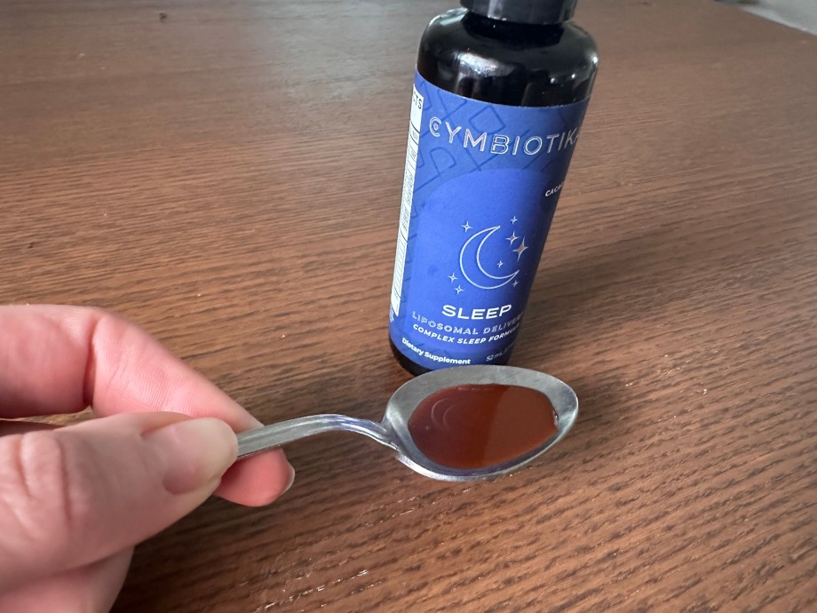A person holds up a spoonful of Cymbiotika Sleep.