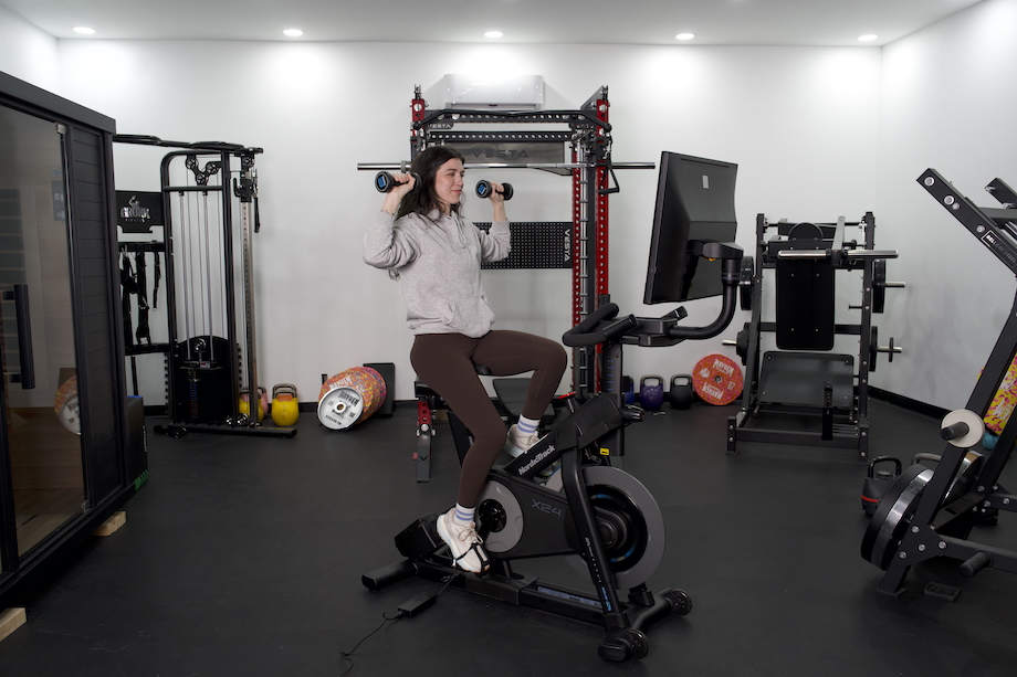 Woman performing a dumbbell workout on the NordicTrack X24 bike