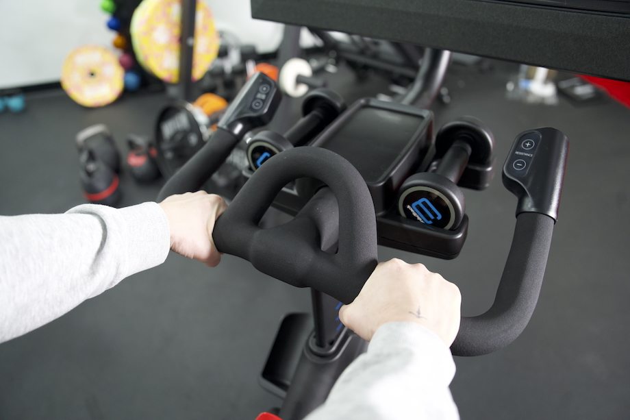 Close view of a woman holding the handlebars on the NordicTrack X24 bike 