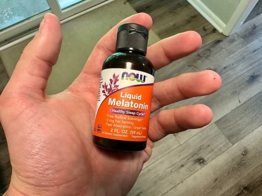 A person holds a bottle of NOW Liquid Melatonin.