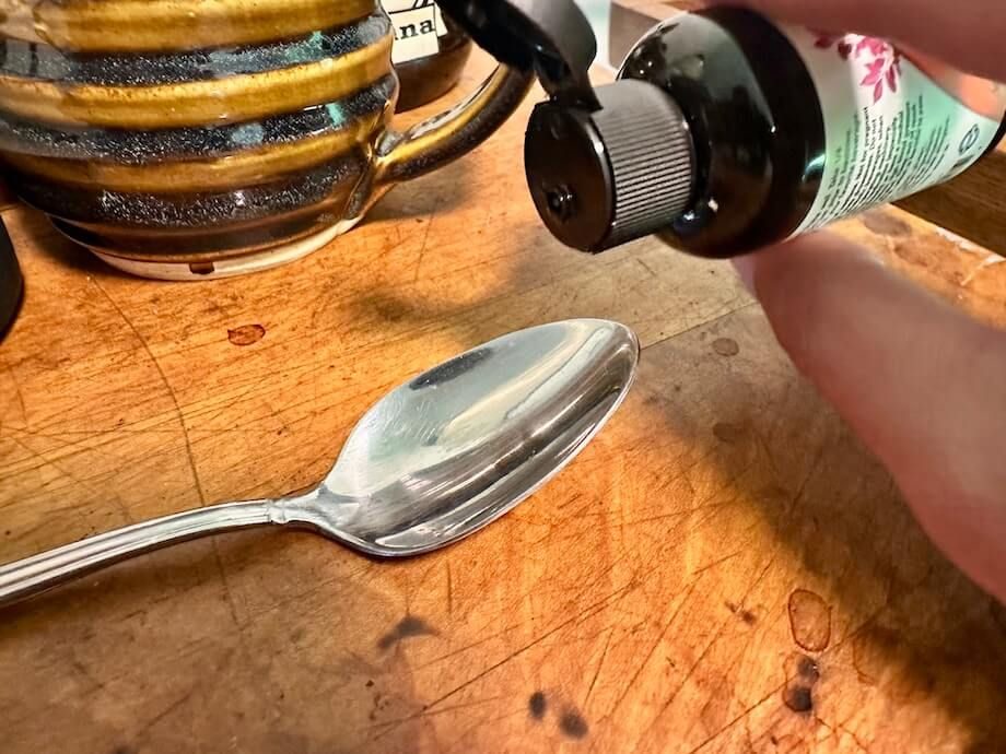 A person begins to pour some NOW Liquid Melatonin into a teaspoon.