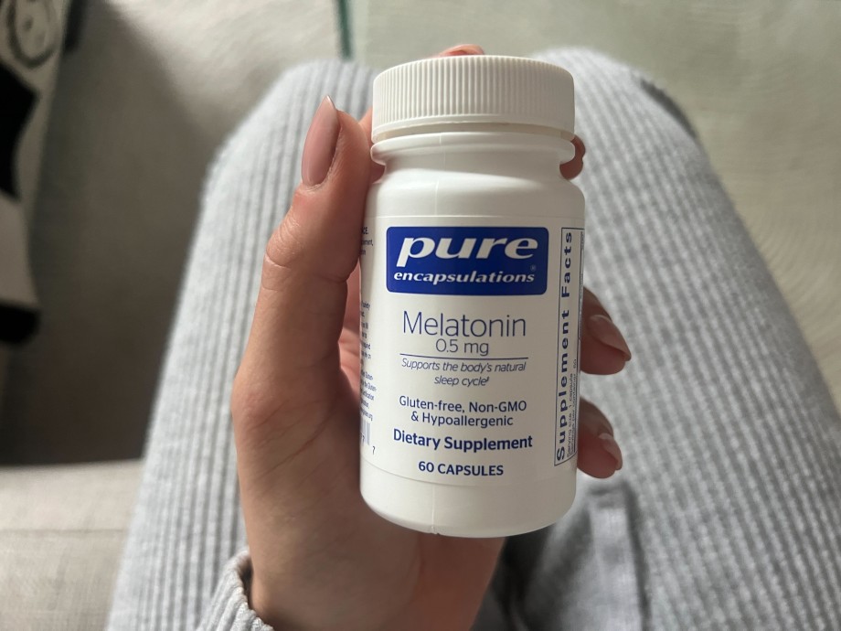A person holding a bottle of Pure Encapsulations Melatonin.