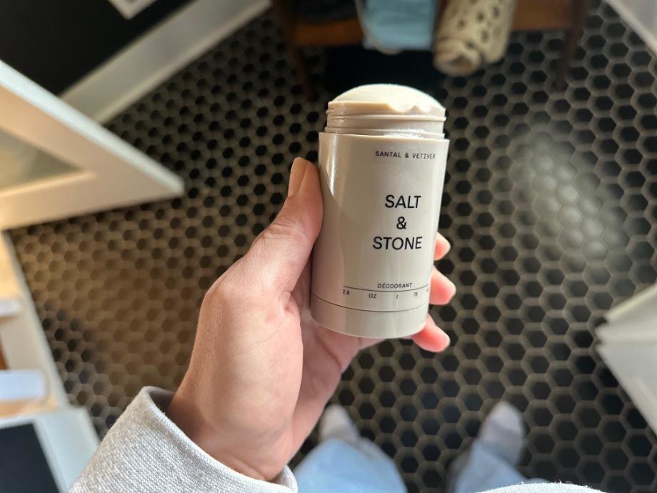 Looking down at a stick of Salt & Stone Deodorant in someone's hand.
