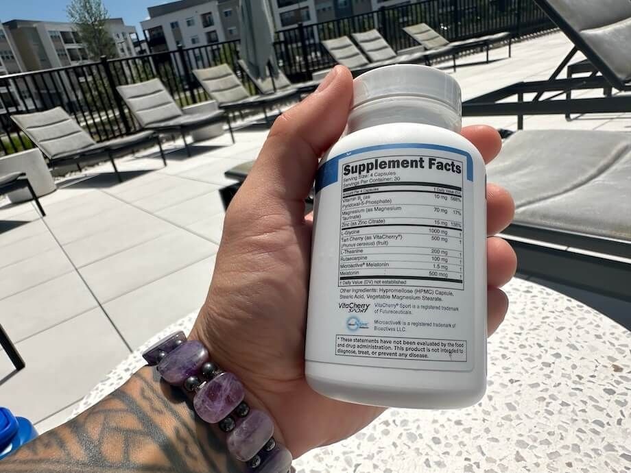 A person holds a bottle of Transparent Labs Sleep Aid & Recover to show the Supplement Facts labels.