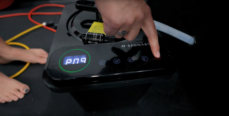 A hand uses the controls for a SaunaBox Go