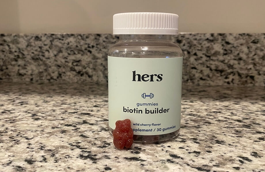 A single Hers Biotin Multivitamin Gummy next to the container