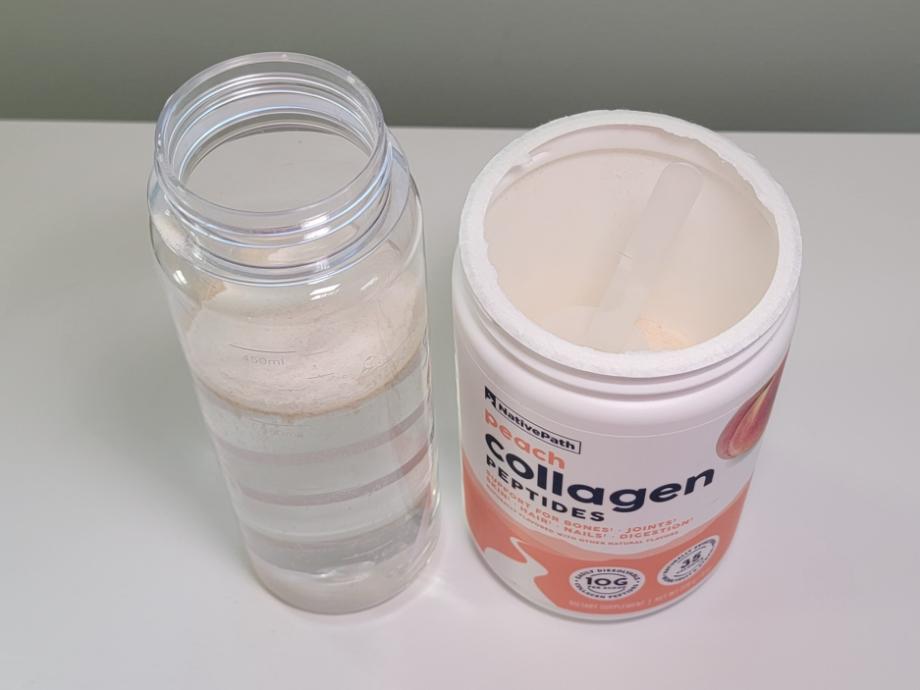 A scoop of NativePath Collagen sits atop water in a shaker bottle prior to mixing