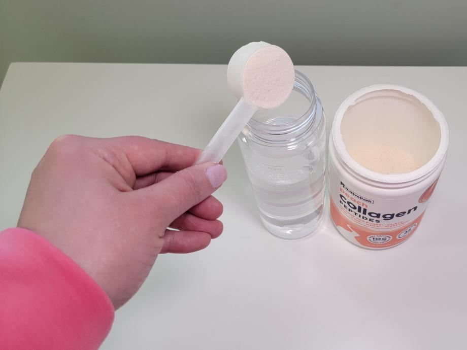 A hand pours a scoop of NativePach Collagen into a bottle filled with water