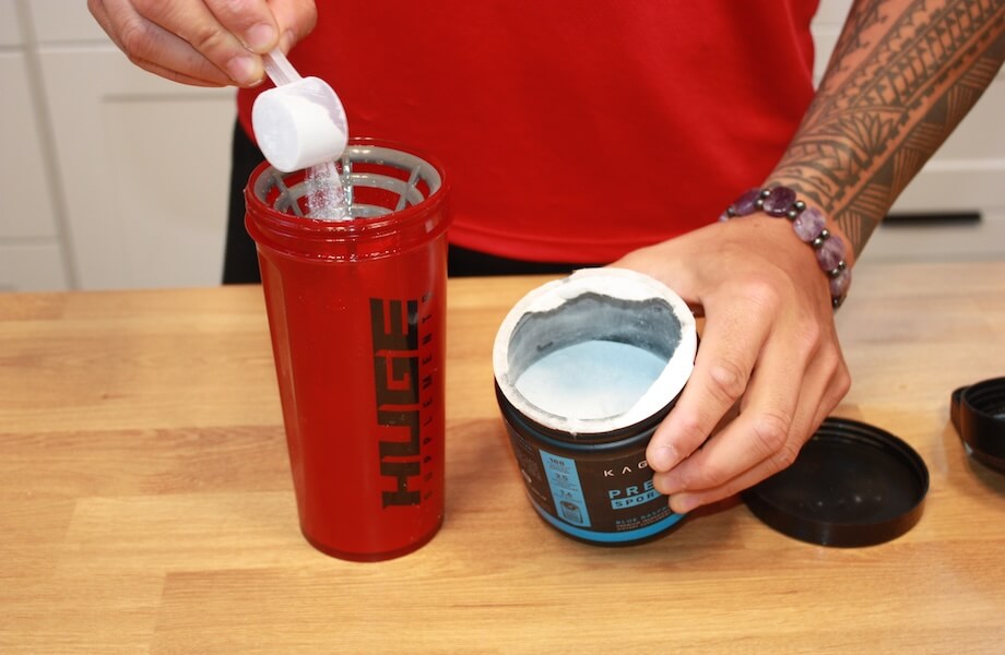 Our tester adding a scoop of Kaged Pre-Workout Sport to their shaker bottle