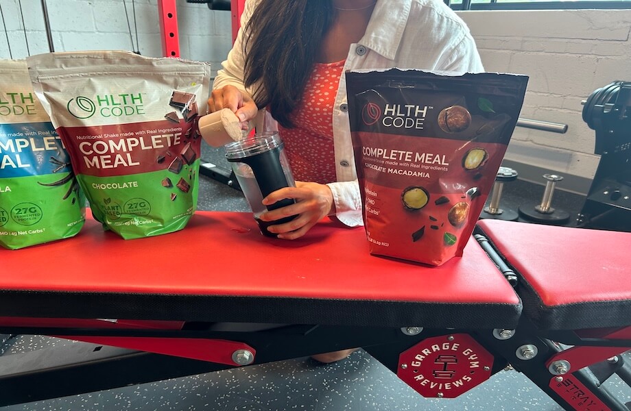 Our tester adding a scoop of HLTH Code Complete Meal to their handheld blender