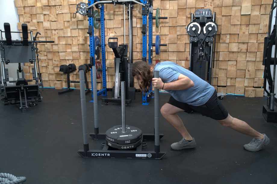 Side view of our tester pushing a Centr x HYROX Competition Power Sled