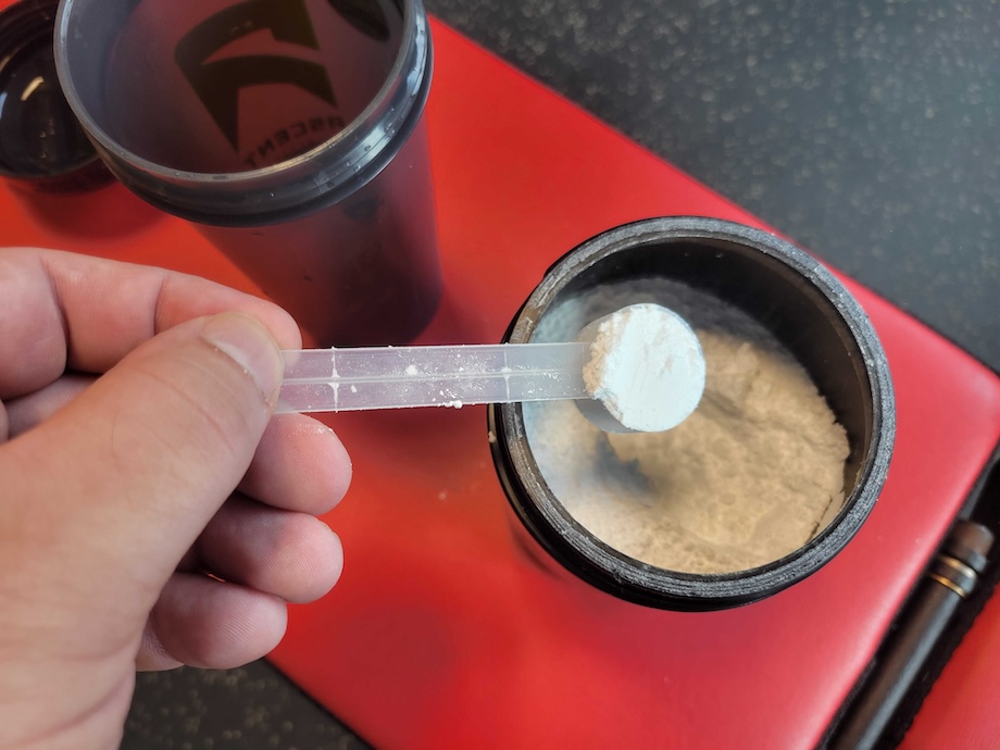 Person measuring a scoop of Sports Research Creatine Monohydrate