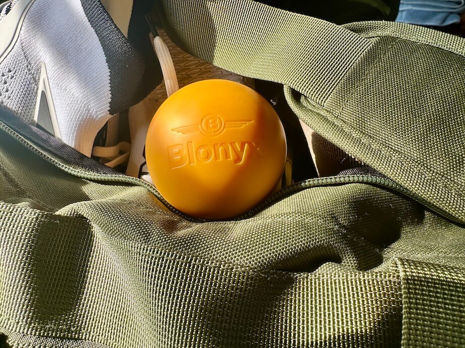 A Blonyx lacrosse ball resting on a gym bag
