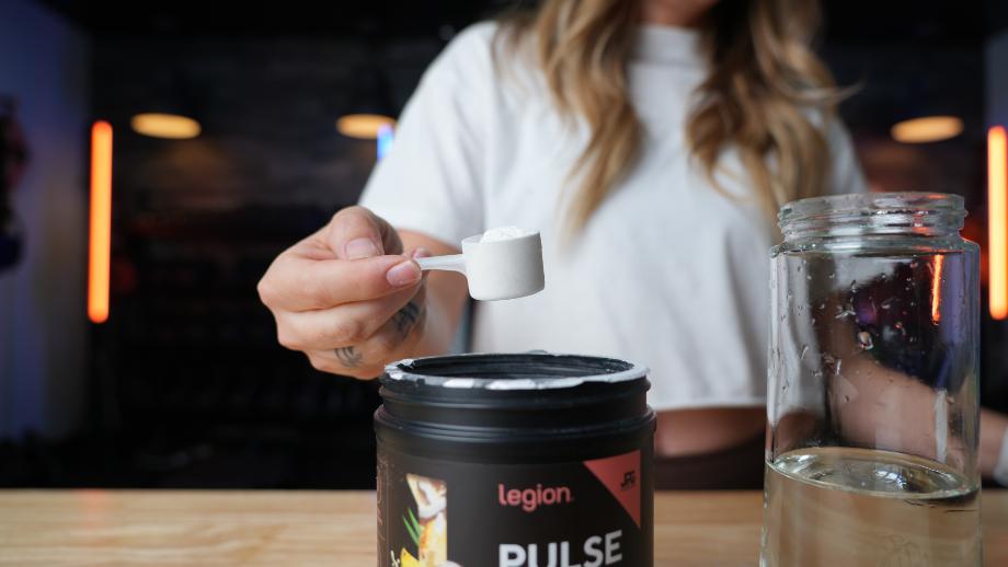 A woman holds a scoop of Legion Pulse