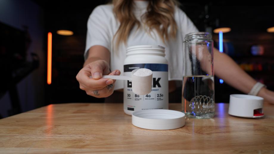 A woman holds a scoop of Transparent Labs BULK