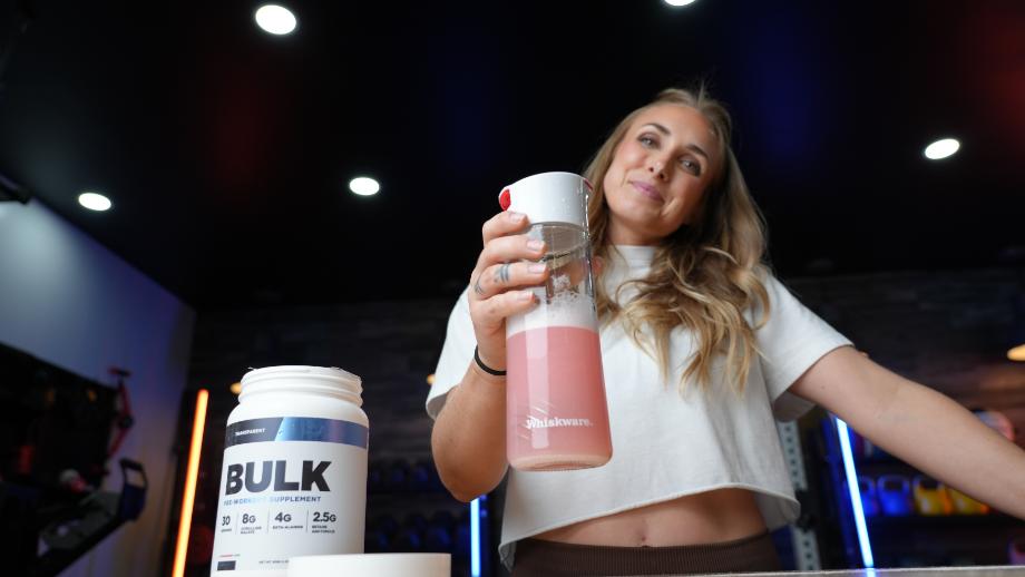 A woman holds a mixed pre-workout drink of Transparent Labs BULK