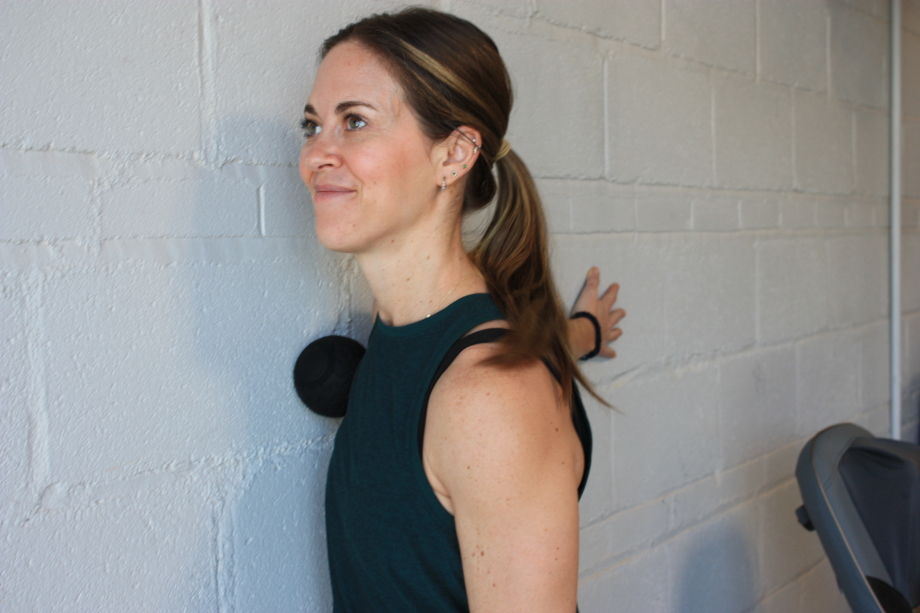 Woman using the Therabody Wave Solo on her chest and shoulder
