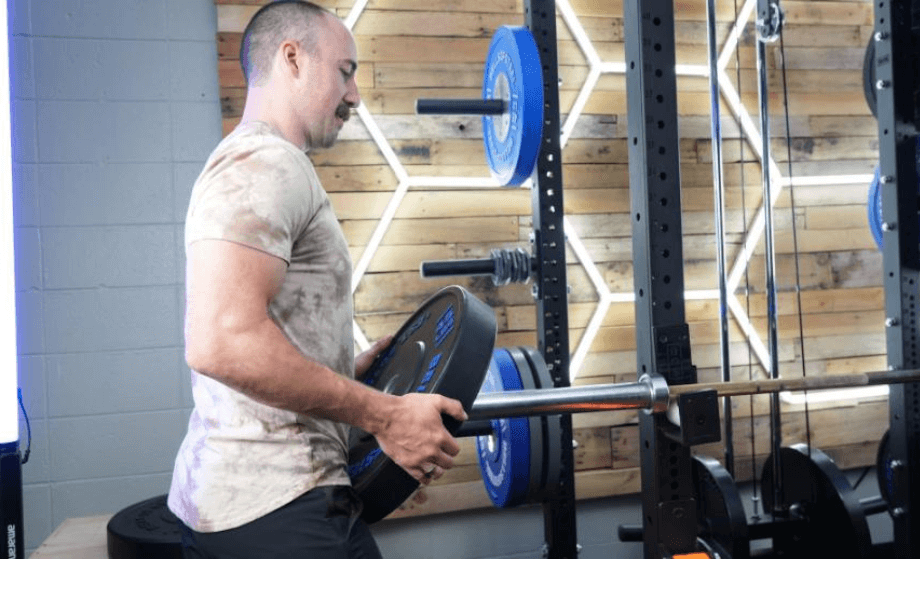 Coop loading a Bells of Steel Dead Bounce Bumper Plate onto a barbell sleeve