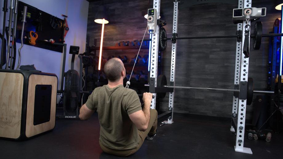 Coop sits on the gym floor while using Beyond Voltra