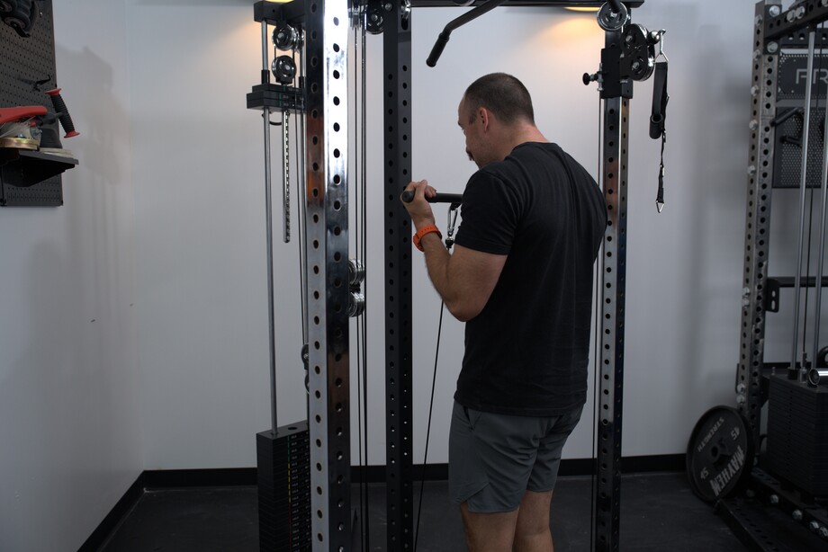 A man performs biceps curls using the Bells of Steel All-In-One Home Gym