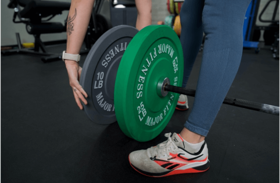 Our tester loading Major Fitness Low Bounce Bumper Plates onto a barbell