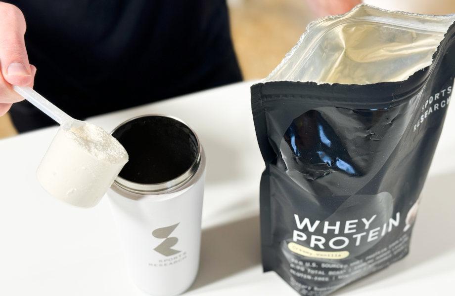 Our tester pouring a scoop of Sports Research Whey Protein into a shaker bottle.
