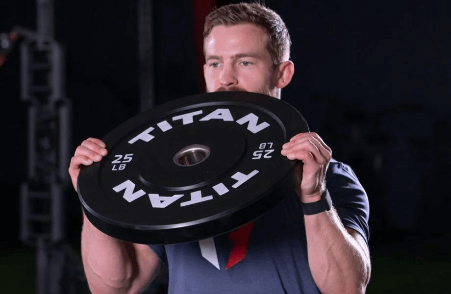 A man curling a 25-pound Titan Fitness Economy Bumper Plate