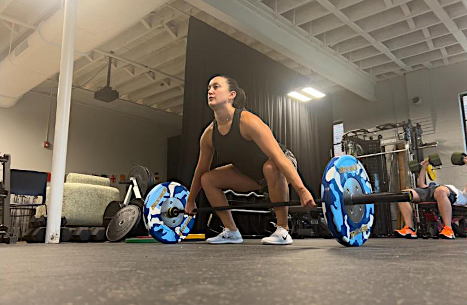 Woman doing a snatch with the Synergee Games Barbell