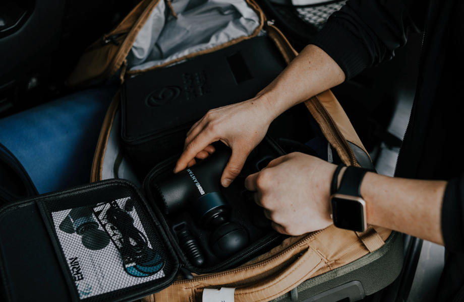 A person lifts an Ekrin Bantam mini-massage gun from it's carrying case.