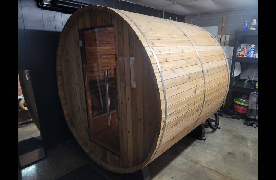 exterior view of almost heaven morgan barrel sauna located inside a garage with the door closed