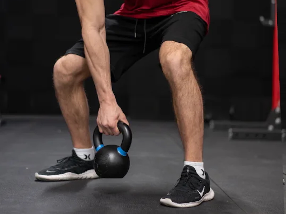 A man performs a one-arm kettlebell swing with the Iron Bull Kettlebell