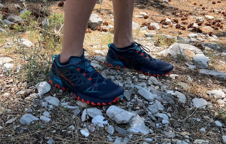 A person wearing La Sportiva Bushido III trail running shoes on a rocky pathway