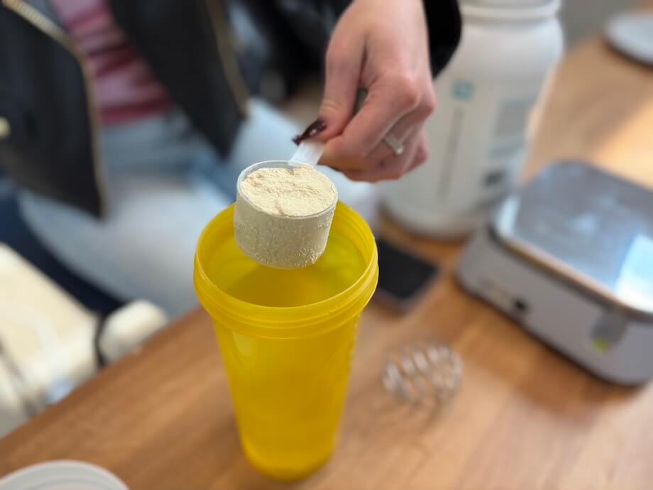 Product tester measuring a scoop of Swolverine Plant Protein