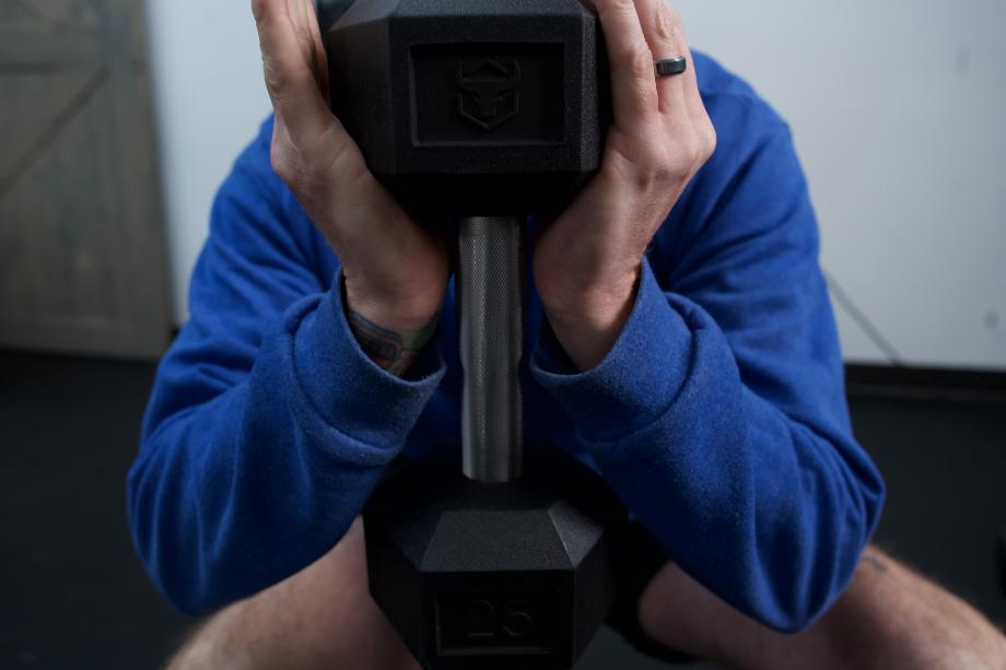 A person does a goblet squat with an Iron Bull Rubber Hex Dumbbell.