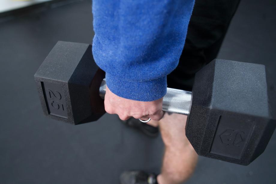 A close look at a hand holding a 25-pound Iron Bull Rubber Hex Dumbbell
