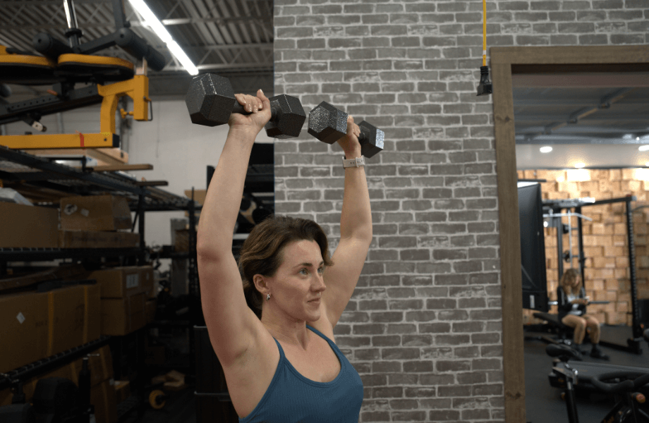 Our tester performing an overhead press with CAP Cast Iron Hex Dumbbells
