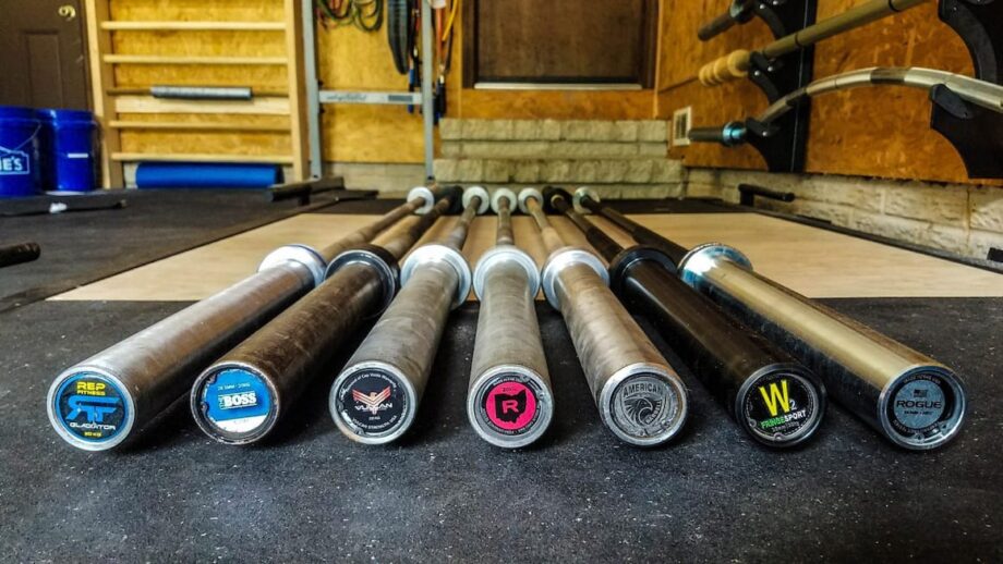 multiple crossfit barbells in a garage gym floor