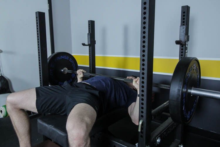 man doing a bench press with the Vulcan Absolute Power Bar V2