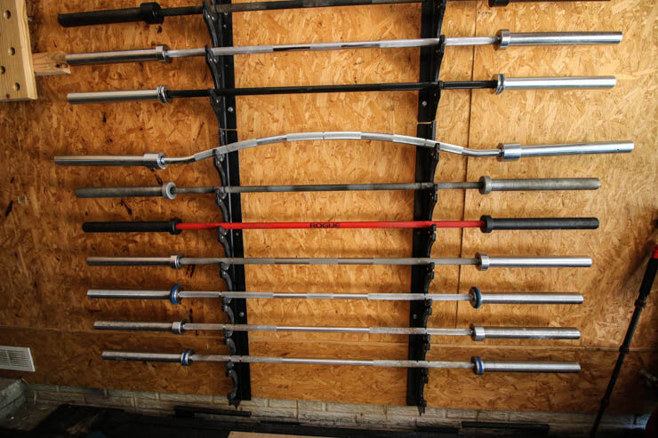 different barbells hung up in a garage gym