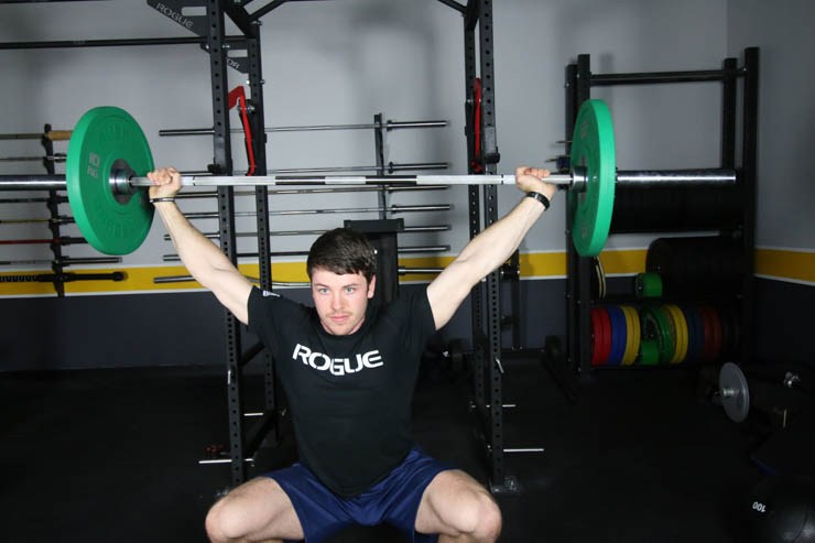 man performing a snatch with the american Barbell Stainless Bearing Bar