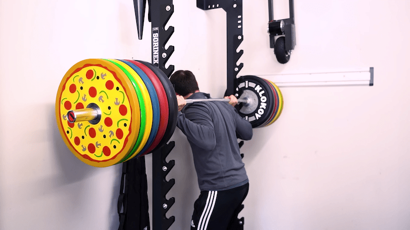 coop testing out the Rogue Fitness RML-90SLIM Rack with a barbell and weighted plates