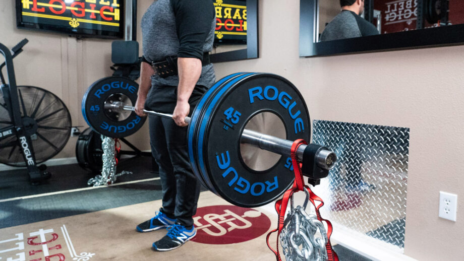 man wearing Pioneer Cut Powerlifting Belt while performing a deadlift with a rogue barbell and rogue bumper plates
